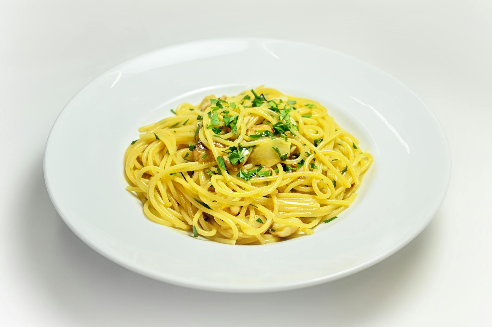 spaghetti aglio e olio with chopped basil on white plate