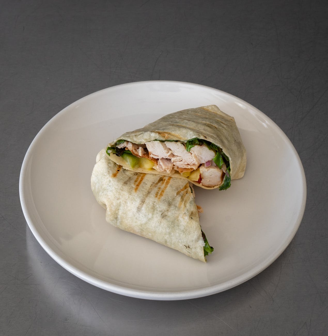 white ceramic round plate with chicken wrap sandwich